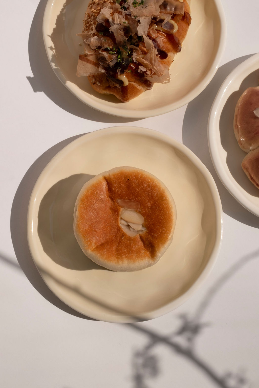 Elegant ceramic plates holding golden buttery pastries and sliced toast in a sunlit bakery