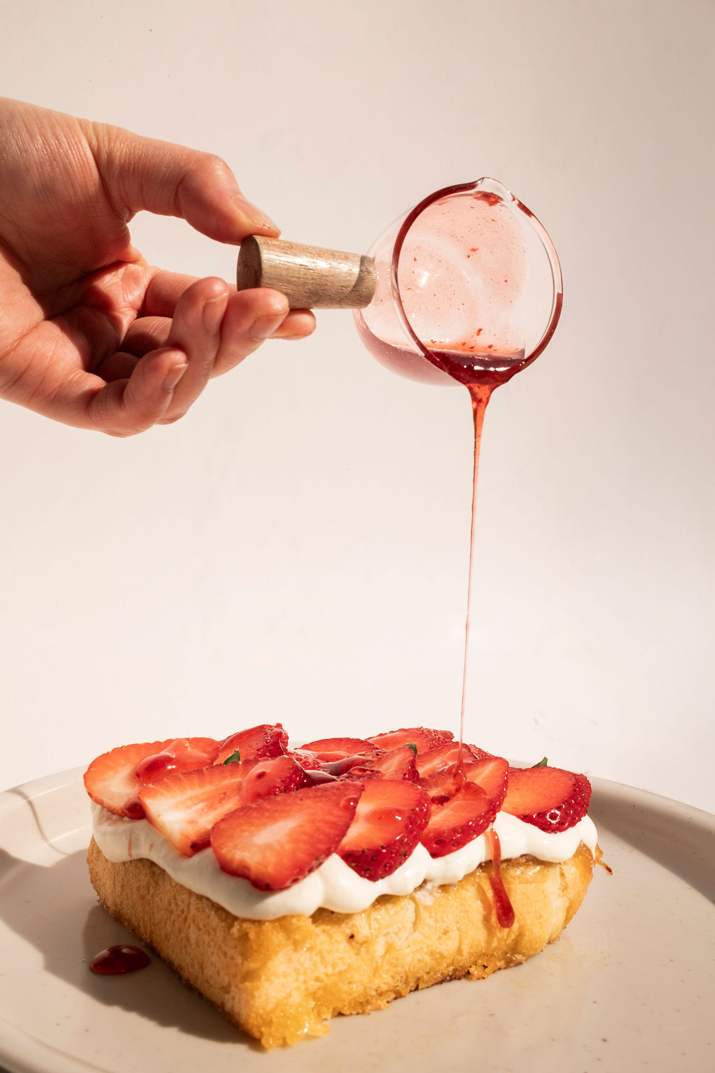 Thick-cut shokupan toast with glossy strawberry syrup and cream, sunlit shadows